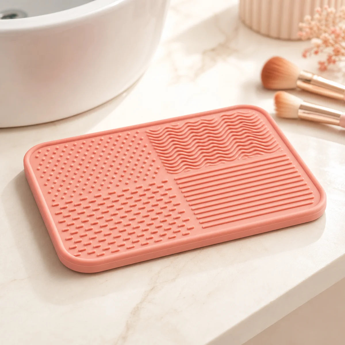 PIMOVO coral makeup brush cleaning mat beside a bright vanity sink